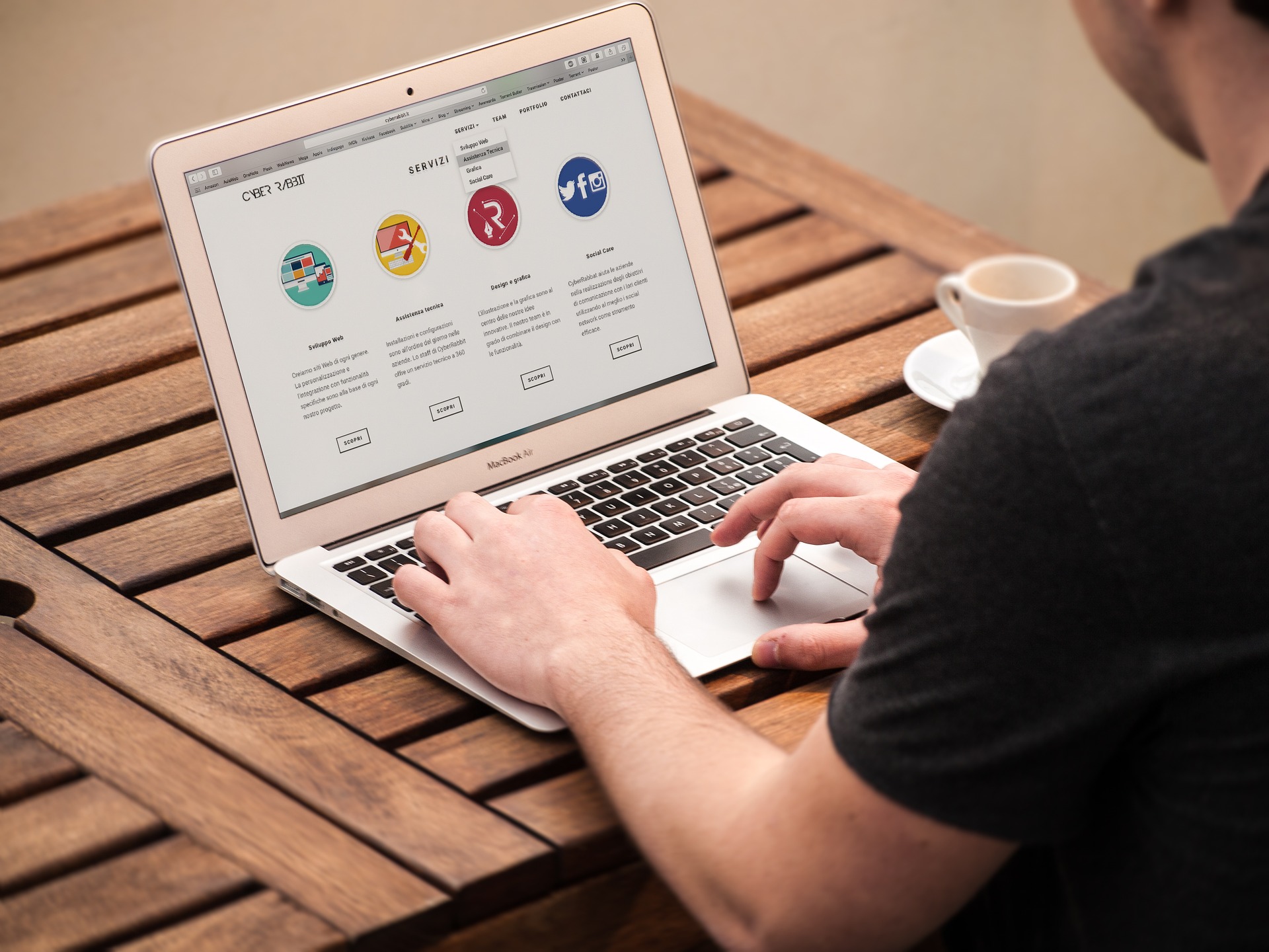 man using a laptop siting at a wooden table