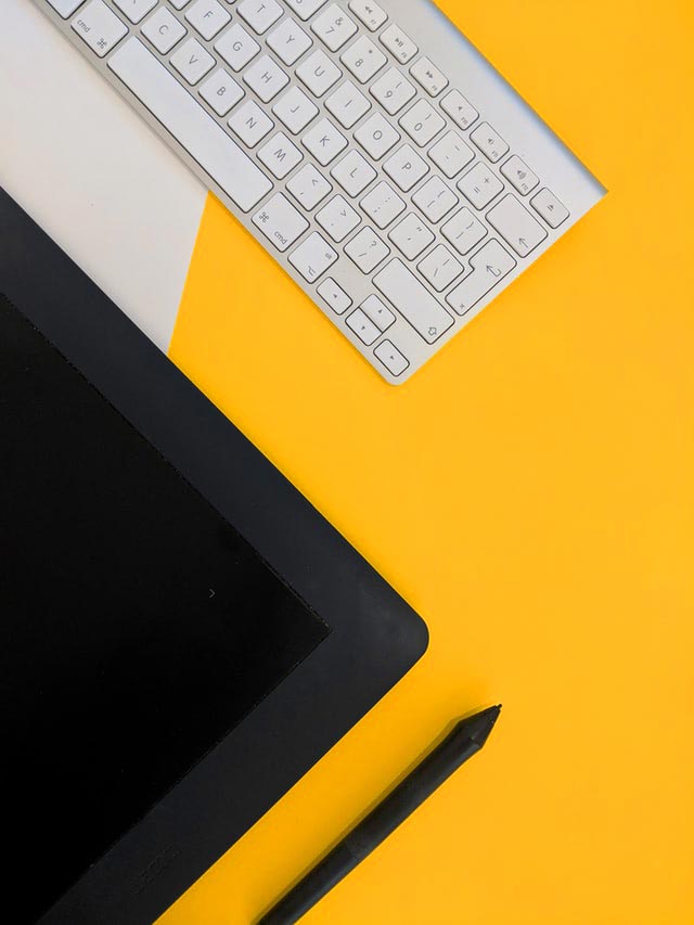 tablet and keyboard on bright yellow background depicting komaya web design services