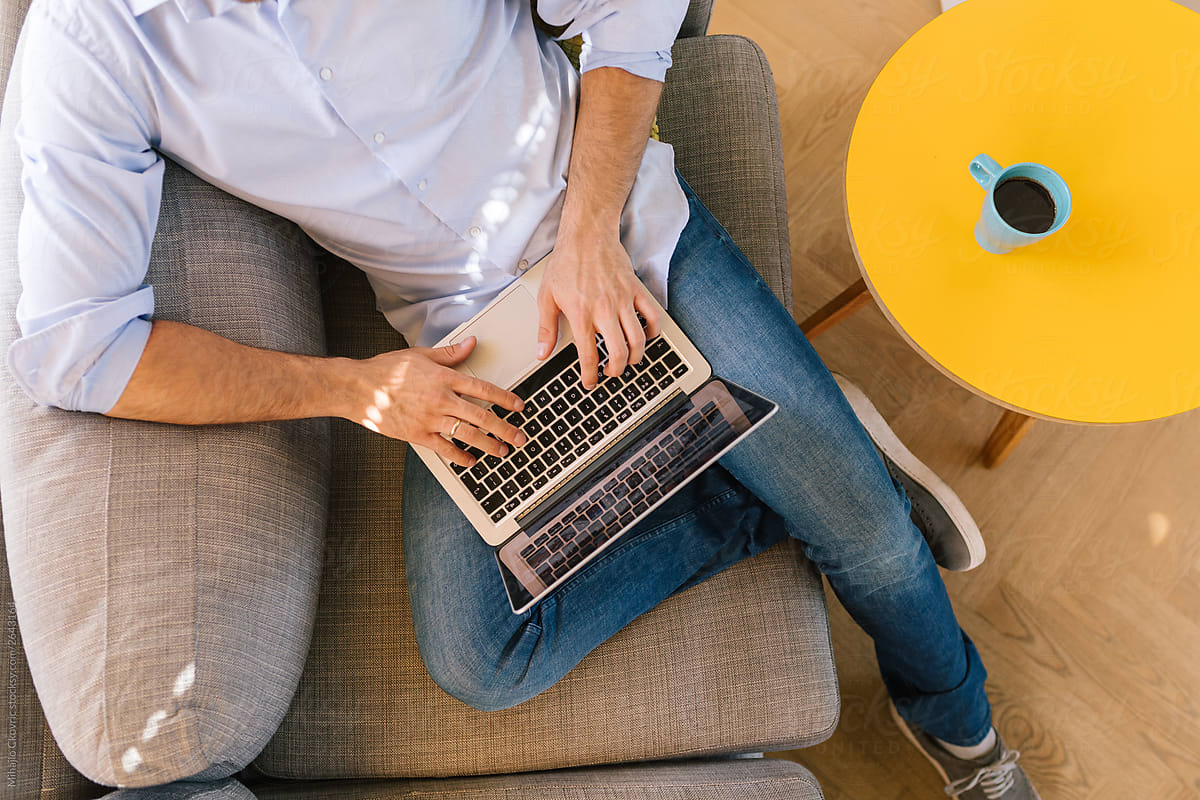 man sitting on couch typing on laptop providing Komaya services